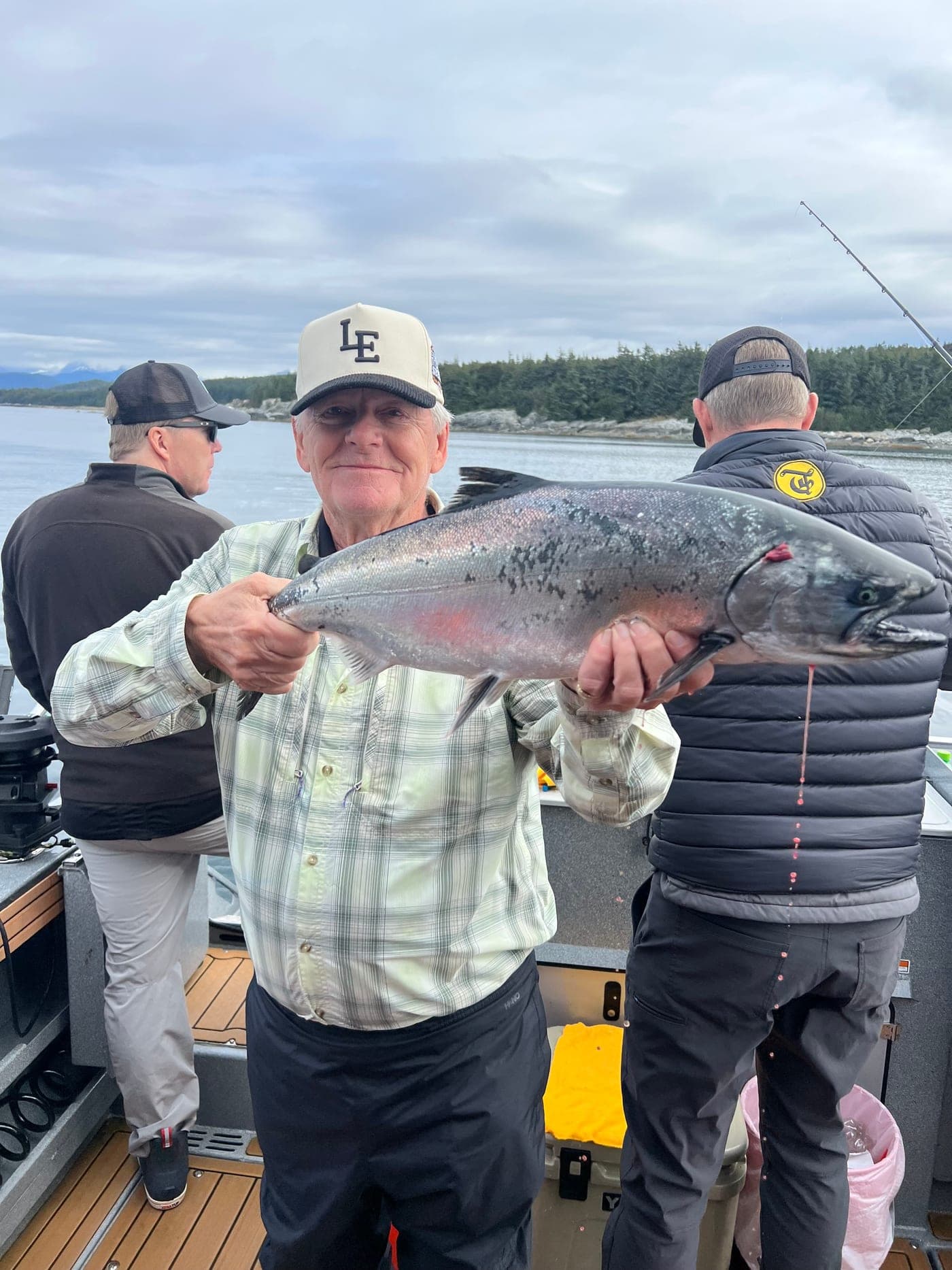 Garth Williams grinning and holding up a freshly caught salmon on deck