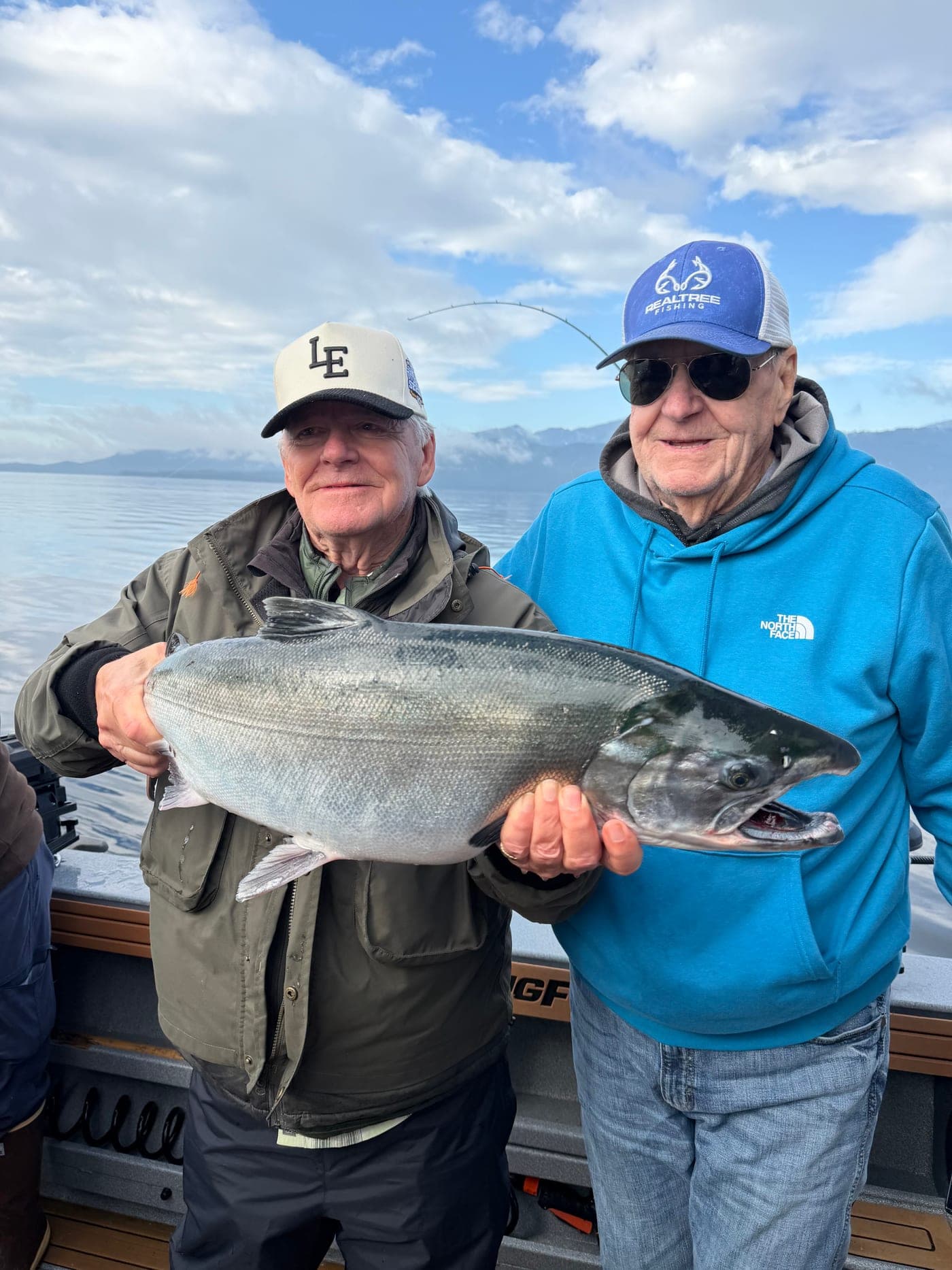 Garth Williams and a friend holding a large salmon on a calm morning